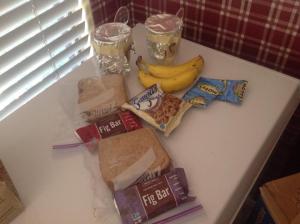 The contents of the first care package prepared by Peter: Stew in Styrofoam cups with a spoon taped to the foil, bananas, fruit snacks, cooks, fig bars, and turkey sandwiches